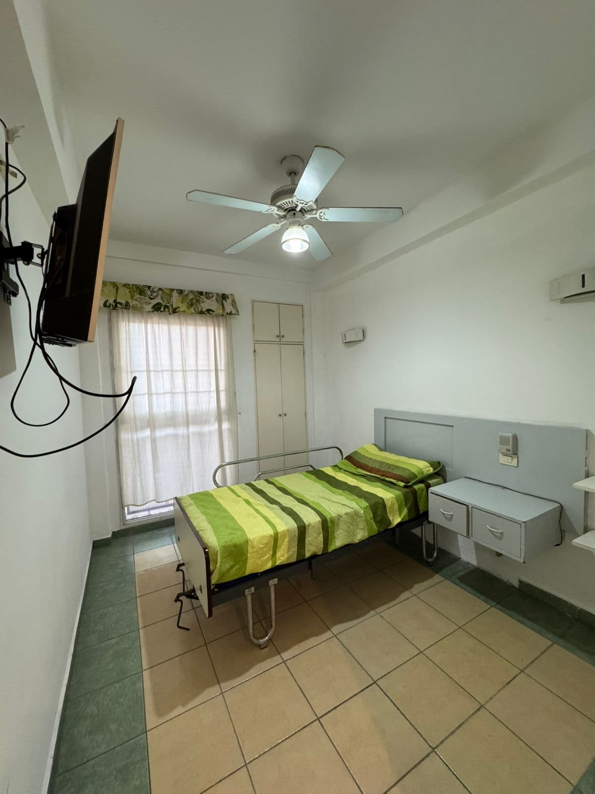 Habitación individual con cama ortopédica, televisor y aire acondicionado para el residente